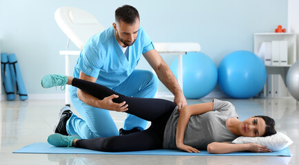 Physiotherapist working with female patient in rehabilitation center