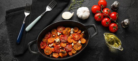 Frying pan with tasty cooked carrots and tomatoes with spices on dark background
