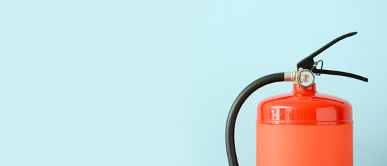 Fire extinguisher on light blue background with space for text, closeup
