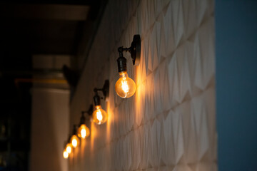 Group of several light bulbs lined up on the wall of a restaurant.