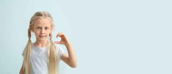 Little deaf mute girl using sign language on light background with space for text