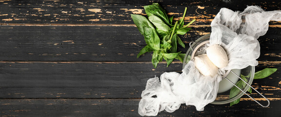 Sieve and bowl with mozzarella cheese on dark wooden background with space for text