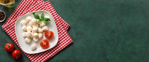Plate of mozzarella cheese and tomatoes on green background with space for text