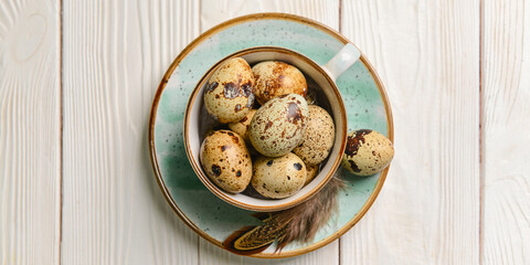 Bowl of fresh quail eggs on light wooden background, top view