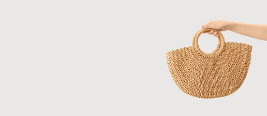Female hand with trendy rattan bag on light background with space for text