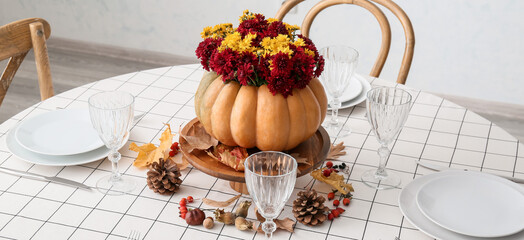 Table setting with autumn floral composition in dining room