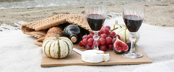 Glasses of red with with cheese, fresh fruits and pumpkins on plaid at resort