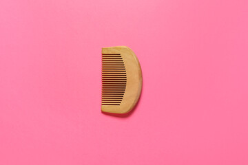 Wooden hair comb for baby on pink background