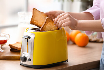 Beautiful young woman making tasty toasts in kitchen, closeup