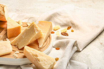 Wooden board with pieces of tasty Parmesan cheese on table, closeup