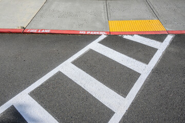 Freshly painted white crosswalk marking leading to a yellow painted ADA sidewalk access in a fire lane
 - obrazy, fototapety, plakaty