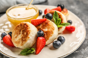 Plate with cottage cheese pancakes, berries and bowl with honey, closeup
