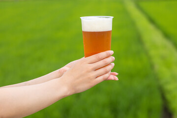 田園の前でビールを持つ手元　Beer
