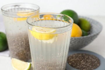 Glasses with water, chia seeds and sliced lemon on white table, closeup