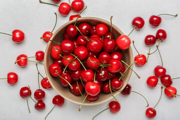 Fototapeta na wymiar Bowl of sweet cherries on light background