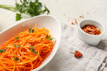 Bowl with carrot salad and ingredients on light background