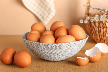 Wicker basket with eggs on beige table