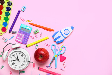 Paper rocket with school stationery, alarm clock and apple on pink background