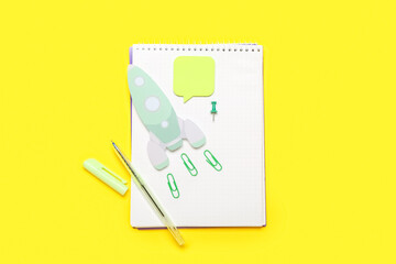 Paper rocket with school stationery on yellow background