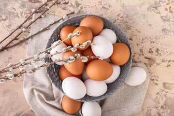 Bowl with chicken eggs and pussy willow branches on grunge background