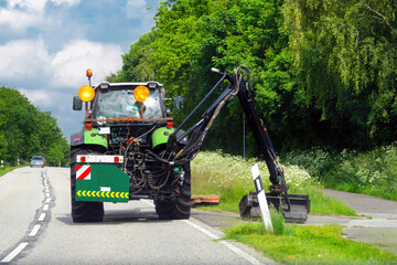 Maintenance of the edge of a road by a brush cutter tractor. Tractor with a mechanical mower mowing...