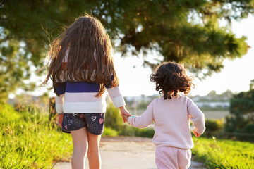 Niñas hermanas juntas y amorosas caminando y dando un paseo en el atardecer al aire libre en el...