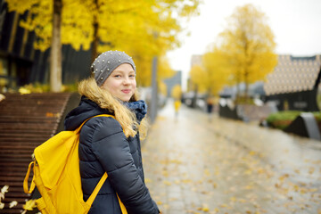 Cute young girl with a backpack heading to school on autumn morning