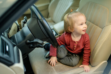 Adorable toddler boy playing in the driver's seat. Cute little son sitting in fathers car.
