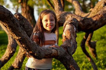 Niña feliz alegre sonriente disfrutando de un hermoso dia al aire libre al exterior en el tronco...