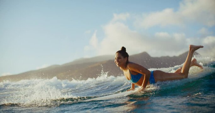 Hawaiian surfer girl paddling out at sunset on longboard, summer lifestyle, surfing in Hawaii