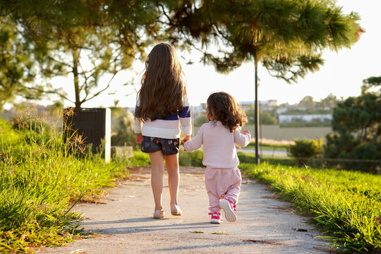 Niñas hermanas amigas primas felices caminando por el camino y dando un paseo en el atardecer al aire libre en el parque disfrutando su amistad en un hermoso día