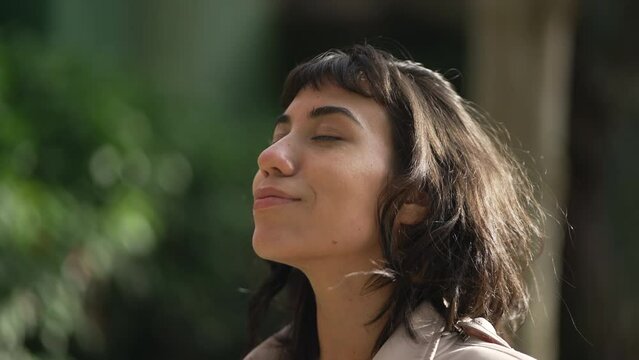 Relaxed young woman with eyes closed standing outside in nature in meditation. Tranquility and relaxation concept. Person in peace and harmony