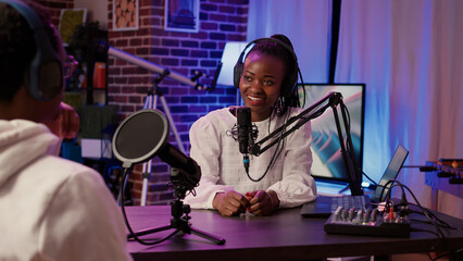 African american couple recording vlog using digital camera while recording podcast using professional microphone and audio equipment. Content creator interviewing famous vlogger in home studio.