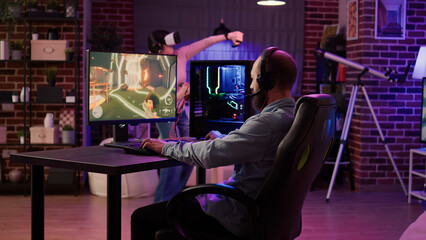 Man playing multiplayer online action rpg on pc while gaming girl is fighting in virtual reality...