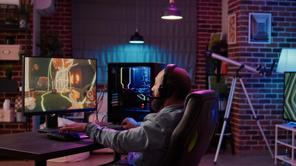 Man playing online first person shooter tournament congratulates team on headset after celebrating victory on gaming pc at home. Professional gamer winning competition doing victory hand gesture. © DC Studio