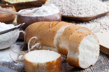 wheat baguette on the table with flour and various plant grains