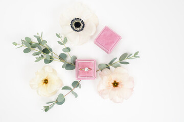 Bridal flat lay background with a velvet ring box, engagement ring and fresh anemone and ranunculus flowers