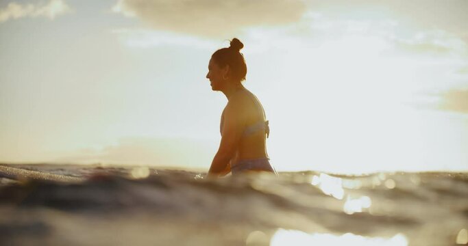 Beautiful Hawaiian surfer girl longboarding at sunset in Hawaii