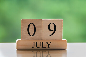 July 9 calendar date text on wooden blocks with blurred background park. Calendar concept