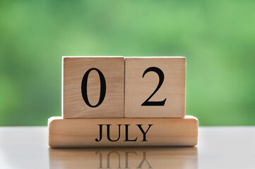 July 2 calendar date text on wooden blocks with blurred background park. Calendar concept