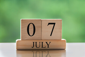 July 7 calendar date text on wooden blocks with blurred background park. Calendar concept