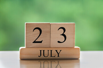 July 23 calendar date text on wooden blocks with blurred background park. Conceptual