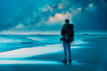 silhouette of a backpacker or traveler looking at the horizon at night with the milky way and the sea in the background