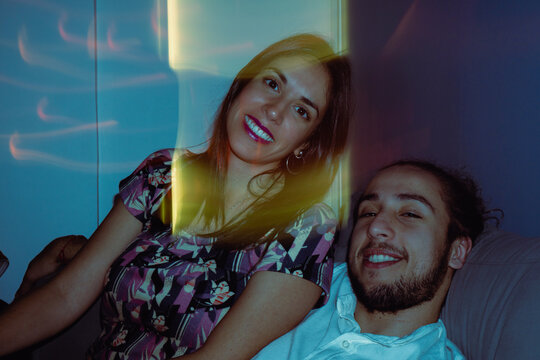 young latin male and female friends together on a sofa inside a party