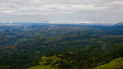 Aerial view of Mountains covered rainforest, trees and blue sky with clouds. Sri Lanka.
