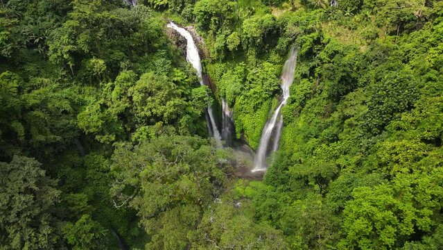 Aerial View Of A Waterfall Hidden In Tropical Rainforest Jungle. Bali, Indonesia. Drone fly-back shot.