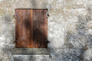 Fototapeta na wymiar old wooden window with closed shutter, shadow on brown wooden frame, no person