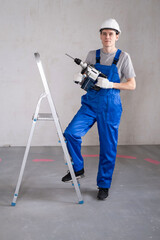 Male Worker in Protective Helmet and Construction Drill in Hands Preparing for Renovating House