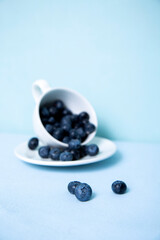 Vertical photo with blueberries on the background of a blurred mug