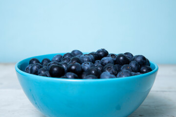 Blueberries in a blue bowl on a wooden table